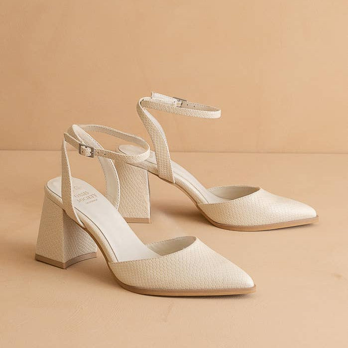 Pair of beige high-heeled shoes on a beige background