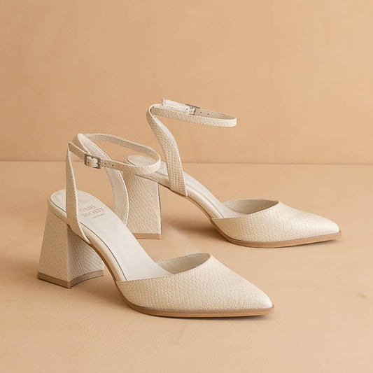 Pair of beige high-heeled shoes on a beige background