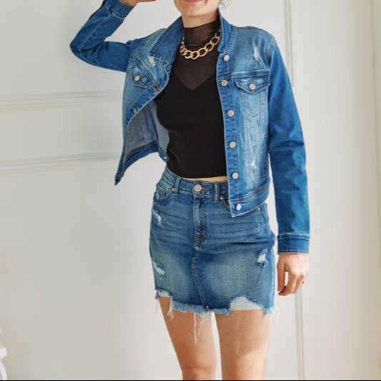 Woman wearing a denim jacket and skirt in a white room