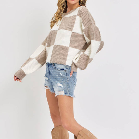 Woman wearing a checkered sweater, denim shorts, and tan knee-high boots on a white background