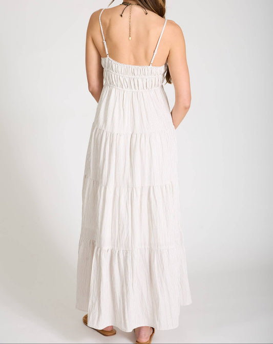 Woman wearing a white dress with thin straps on a plain background