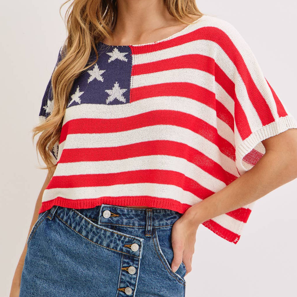 Woman wearing a red, white, and blue top with an American flag design on a plain background