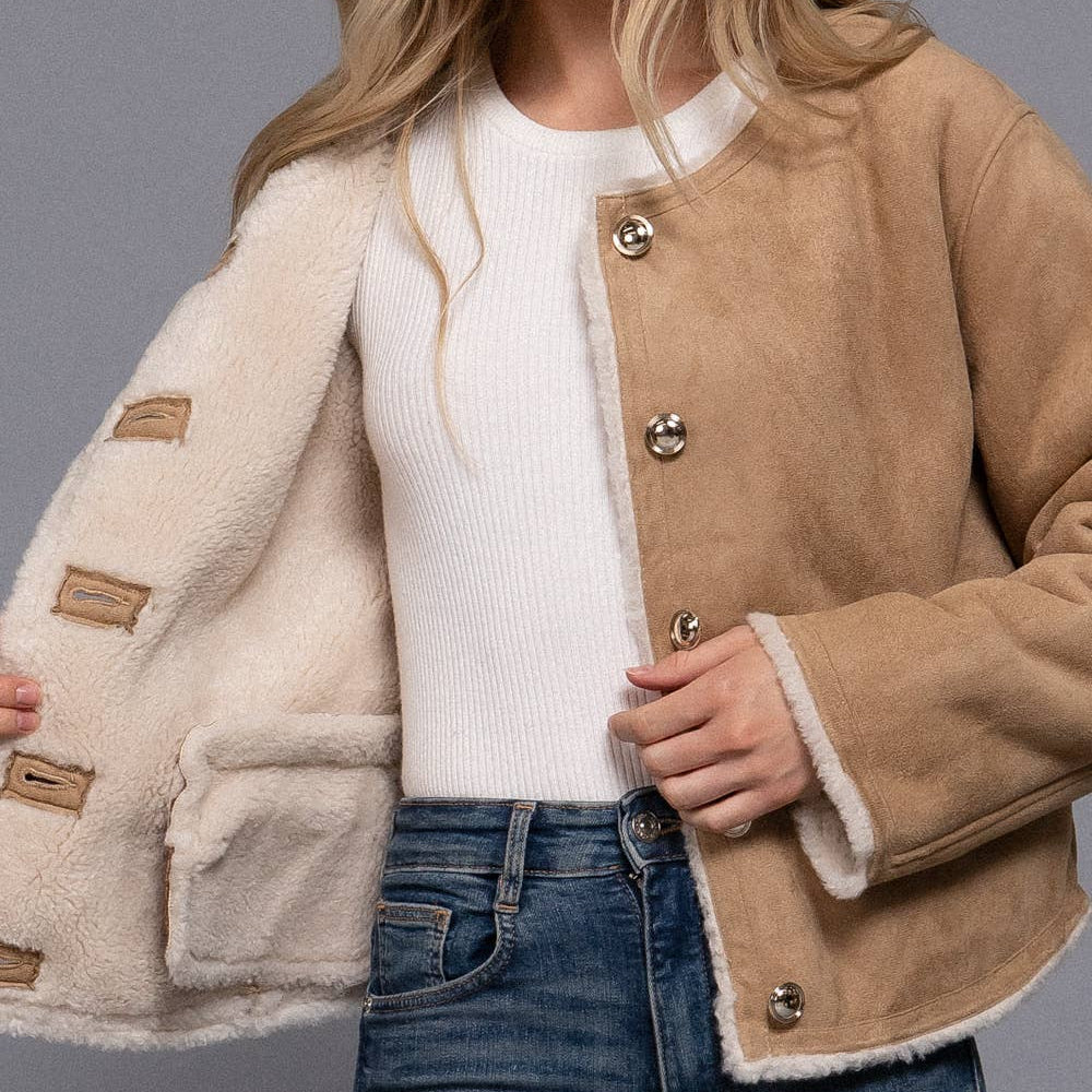 Woman wearing a beige and white coat with a plain background