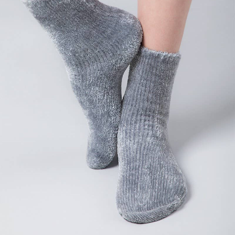 A pair of heather gray ribbed ankle socks worn on a person's feet, shown against a clean light gray studio background.