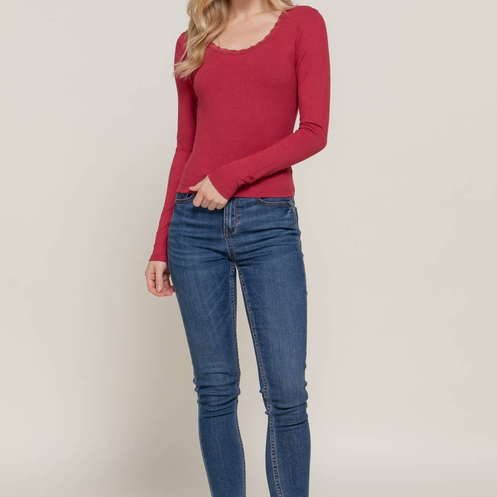 Woman wearing a red sweater and blue jeans on a beige background