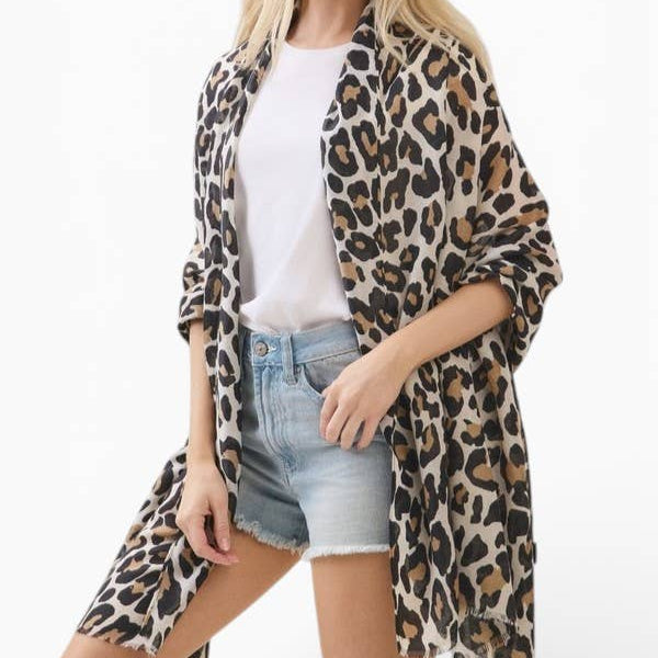 A woman modeling a leopard print open-front cardigan over a white t-shirt and denim shorts, photographed against a clean white studio background.