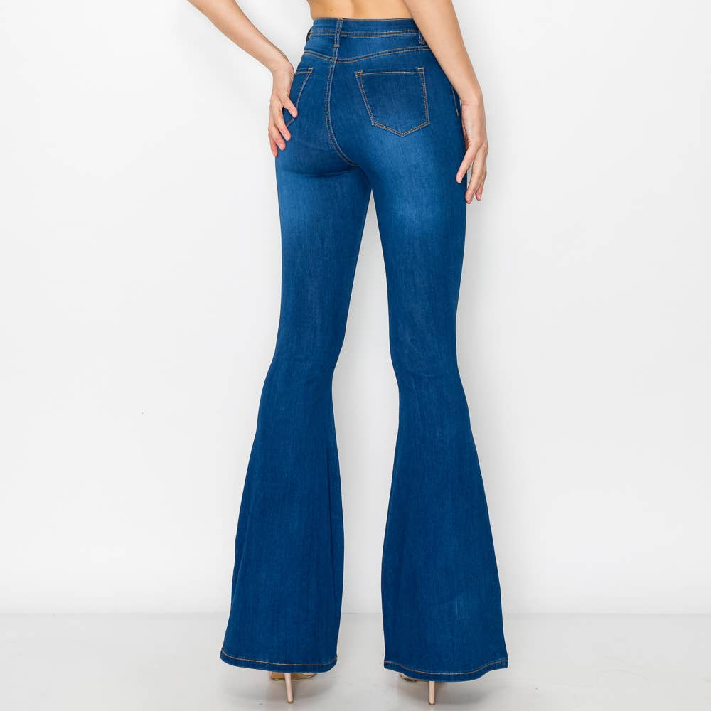 Woman wearing blue flared jeans and a white top on a white background