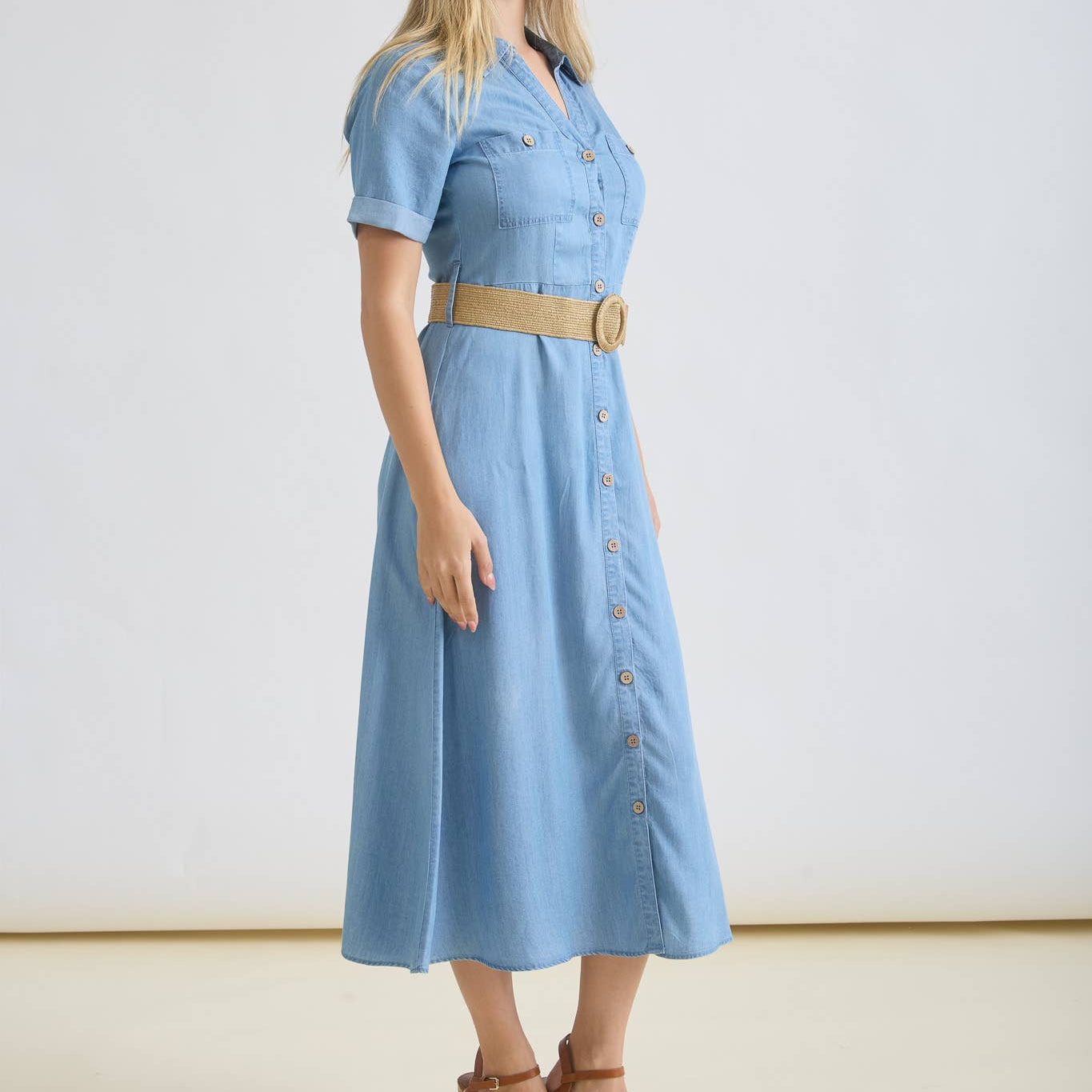 Woman wearing a light blue dress with a belt on a white background