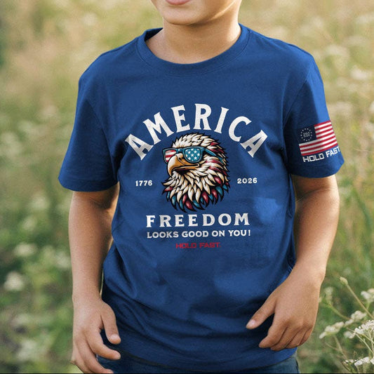 Child wearing a blue t-shirt with 'America Freedom' design in a field