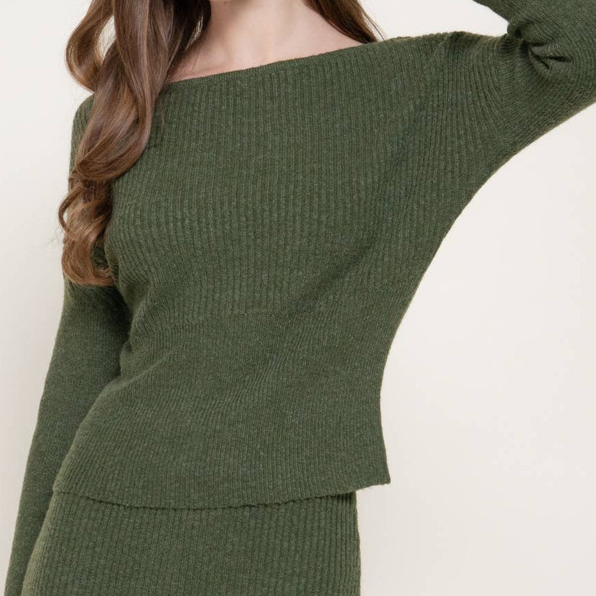 A woman modeling a ribbed knit two-piece set in olive green, featuring a wide-neck long-sleeve top and a matching fitted skirt, against a plain off-white background.
