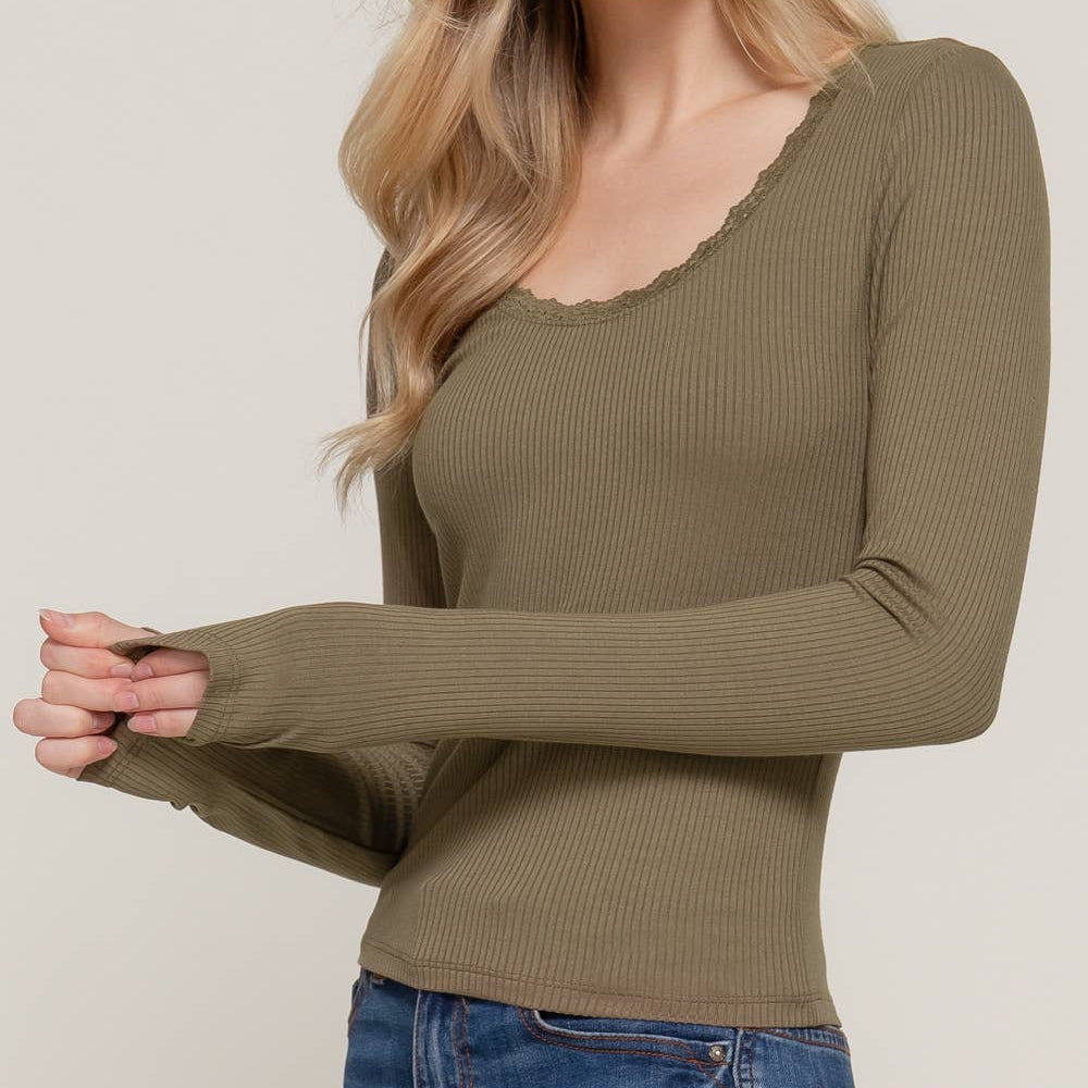 Woman wearing a green ribbed long-sleeve top against a plain background