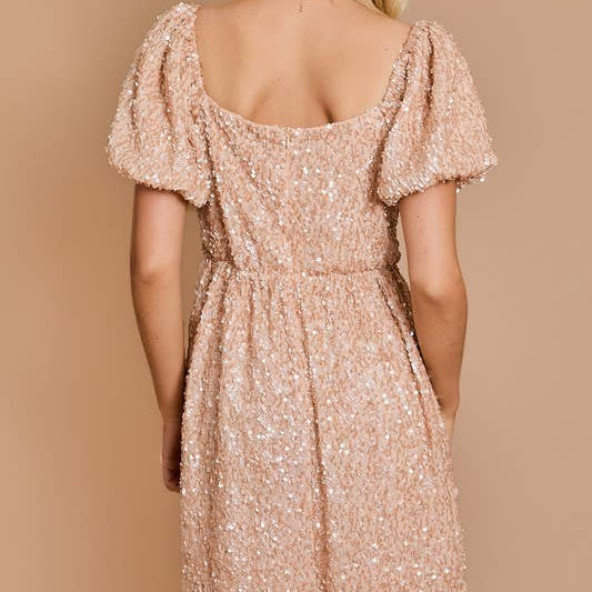 Woman wearing a sparkly pink dress against a beige background