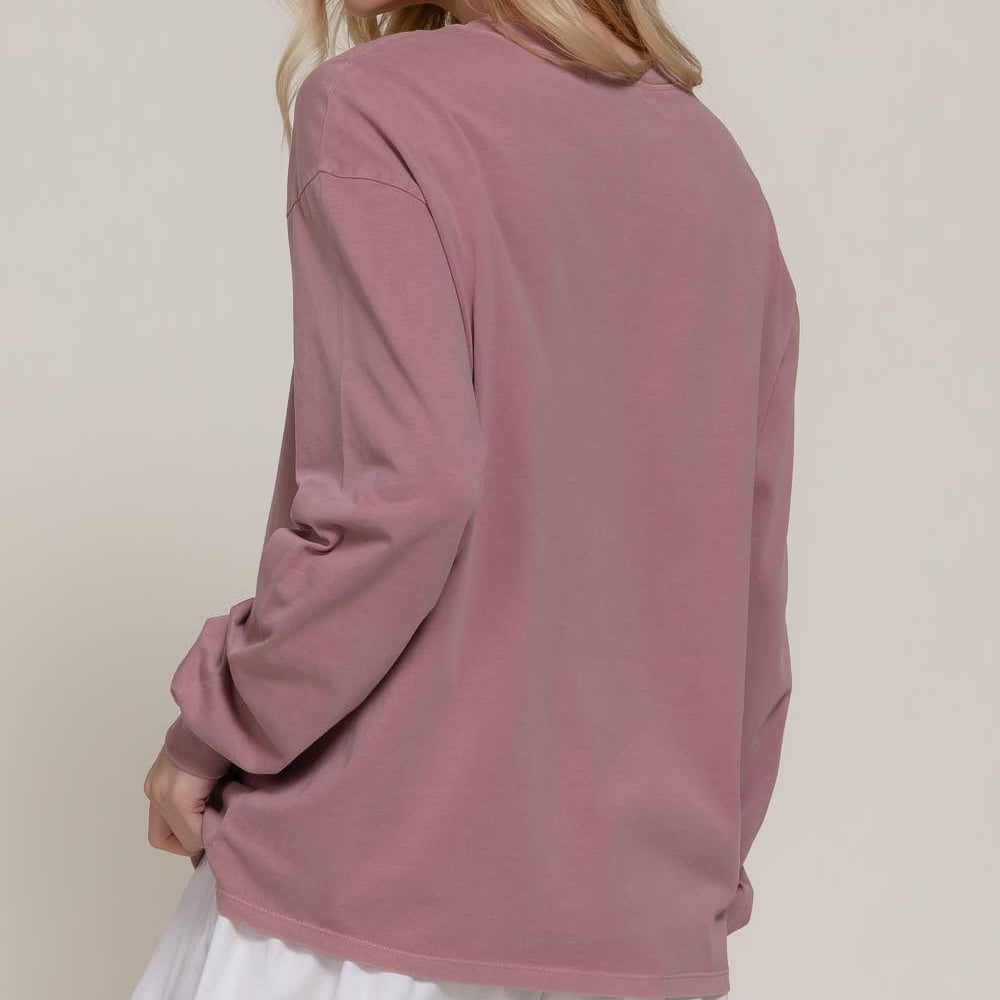 Woman wearing a pink long-sleeve top and white skirt on a beige background