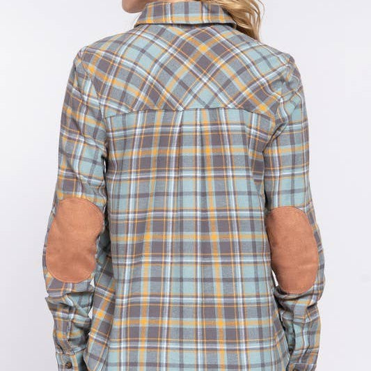 Plaid shirt with elbow patches worn by a person on a white background
