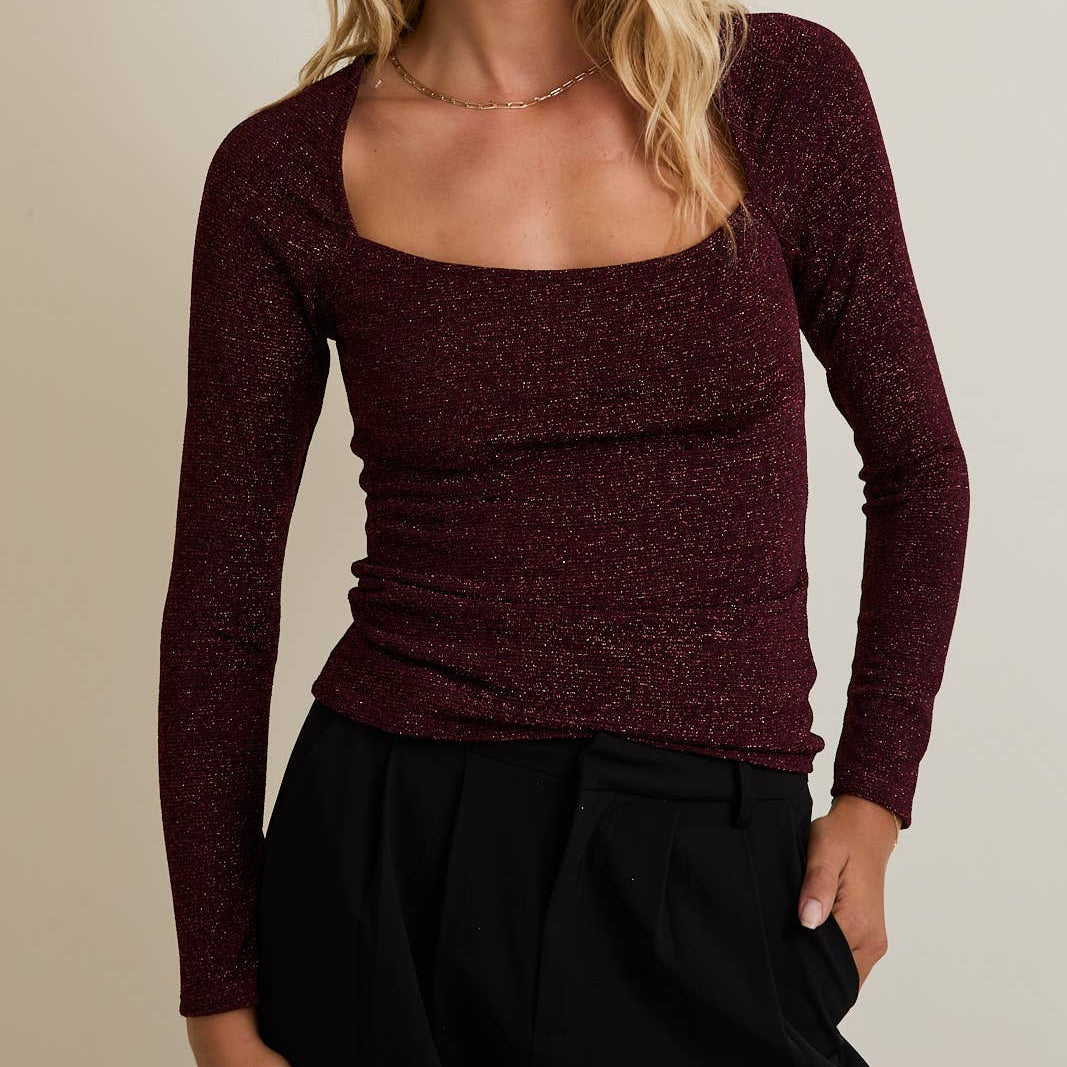 Woman wearing a burgundy long-sleeve top against a neutral background