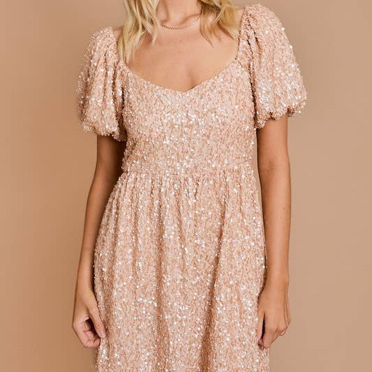 Woman wearing a sparkly beige dress against a beige background