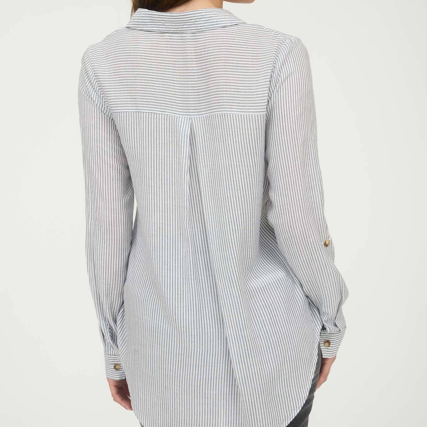 Woman wearing a long, light-colored striped shirt on a white background