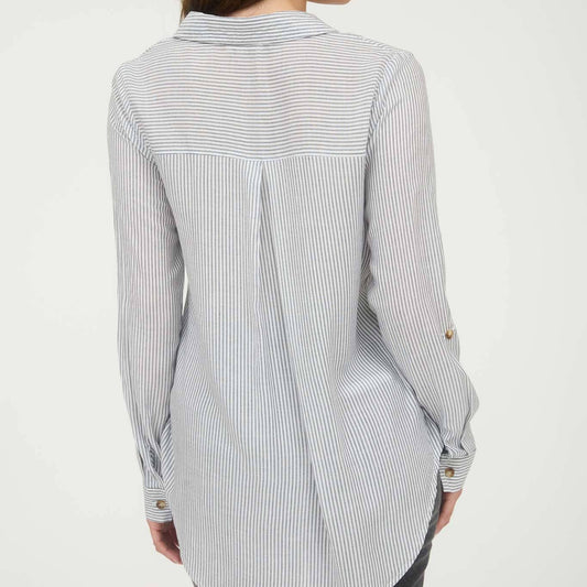 Woman wearing a long, light-colored striped shirt on a white background