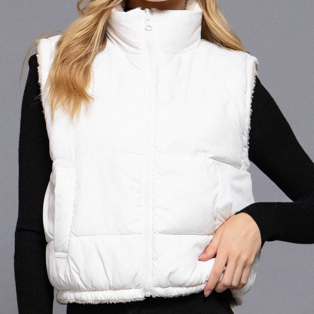 Woman wearing a white puffer vest against a gray background