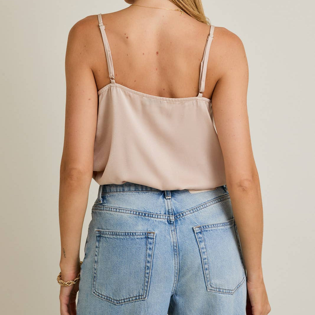 Woman wearing a beige top and blue jeans on a plain background