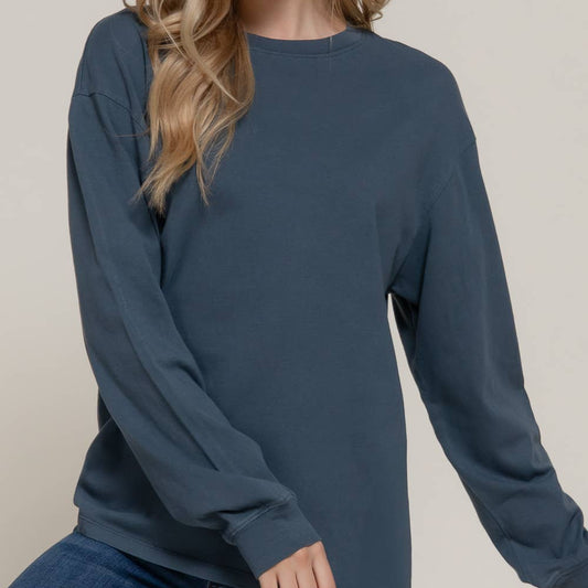 Woman wearing a blue long-sleeve top against a plain background
