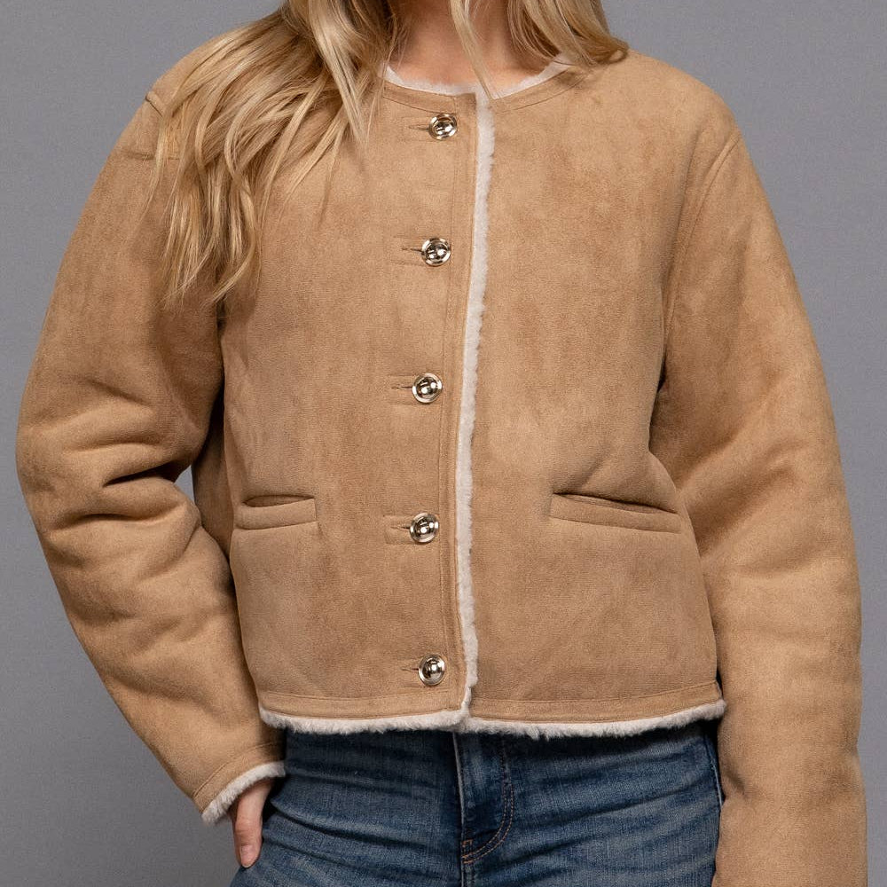 Woman wearing a beige jacket with white trim against a gray background