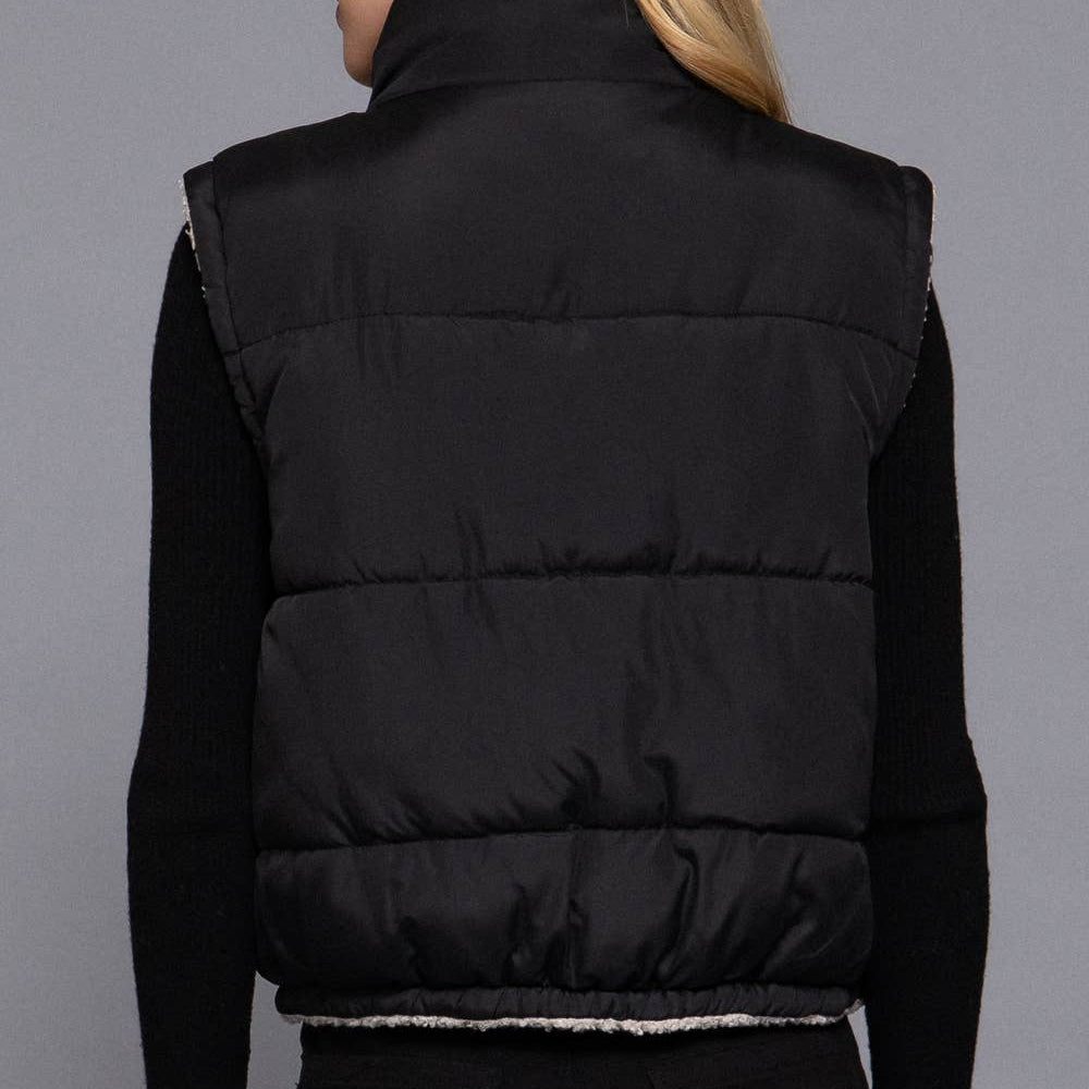 Person wearing a black puffer vest on a gray background