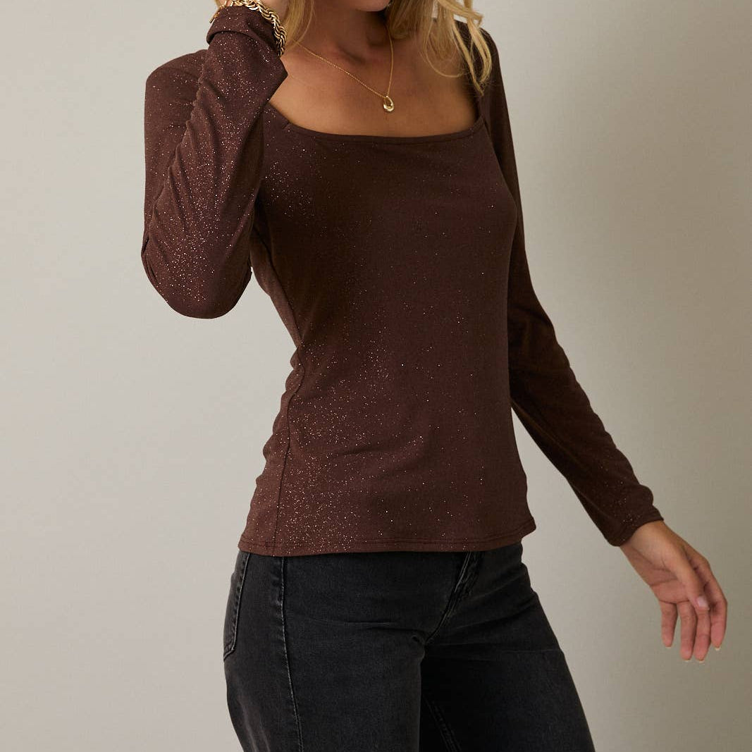 Woman wearing a brown long-sleeve top against a plain background