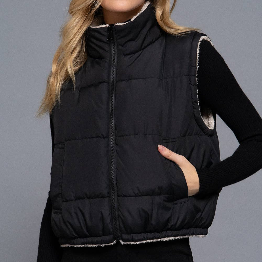 Woman wearing a black puffer vest against a gray background