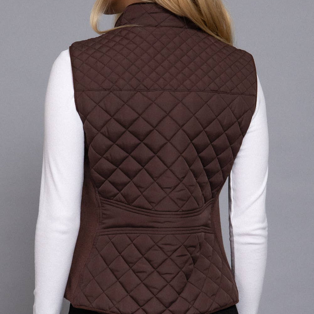Person wearing a brown quilted vest on a gray background