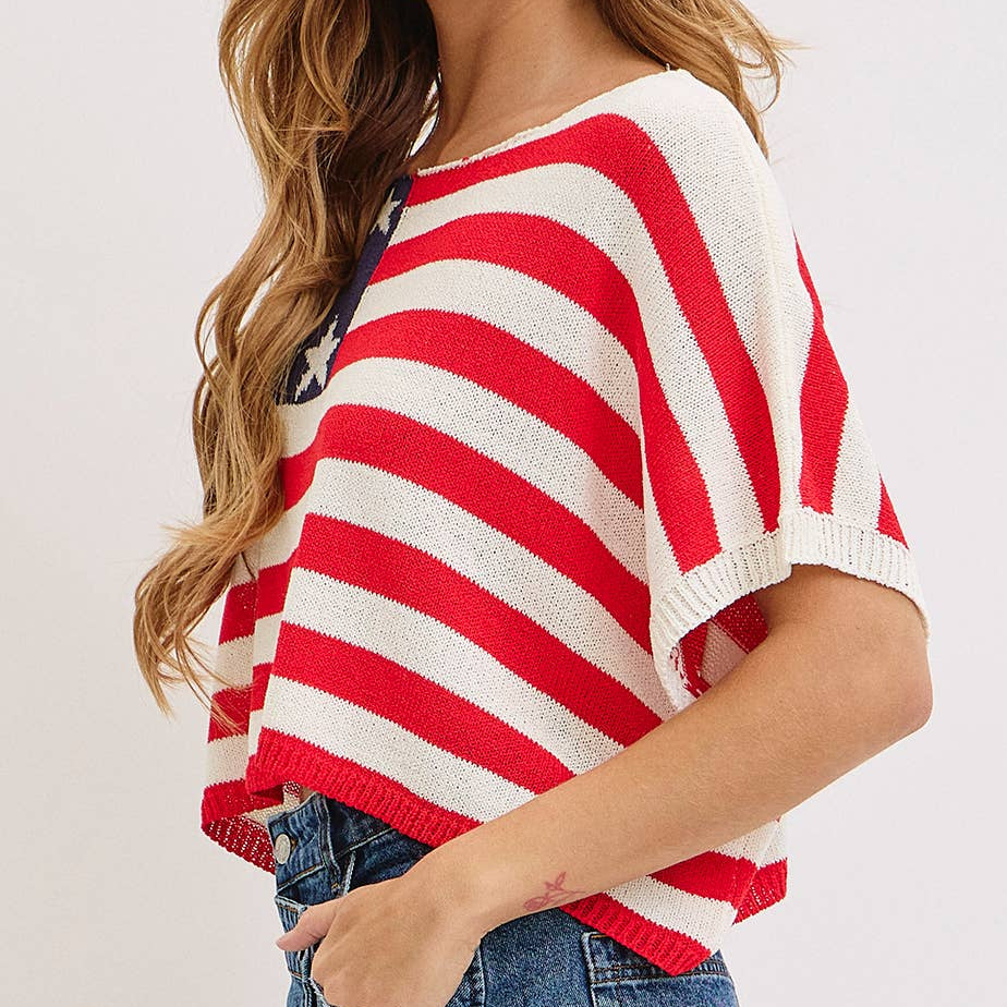 Woman wearing a red and white striped sweater with blue jeans on a plain background
