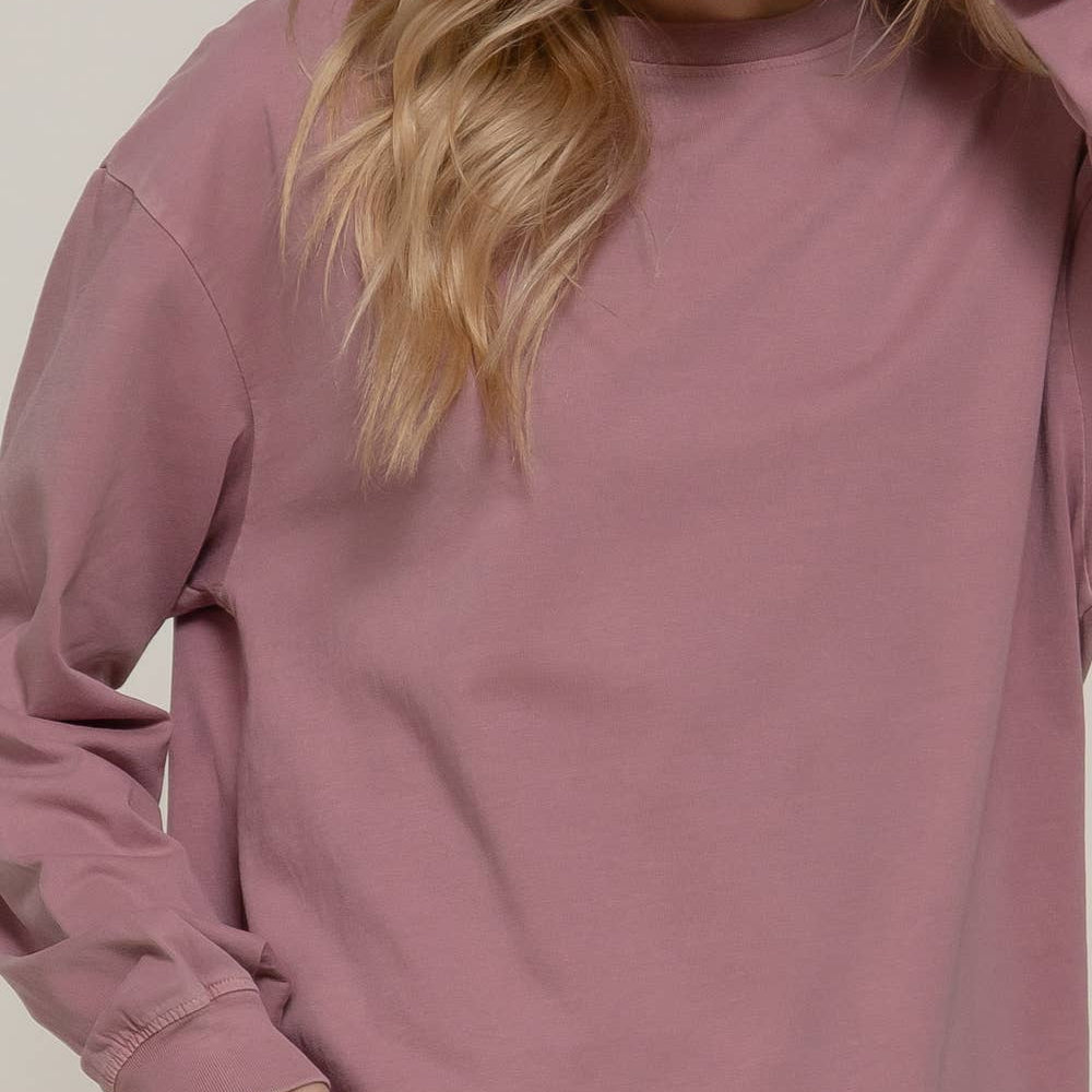 Woman wearing a mauve long-sleeve top against a plain background