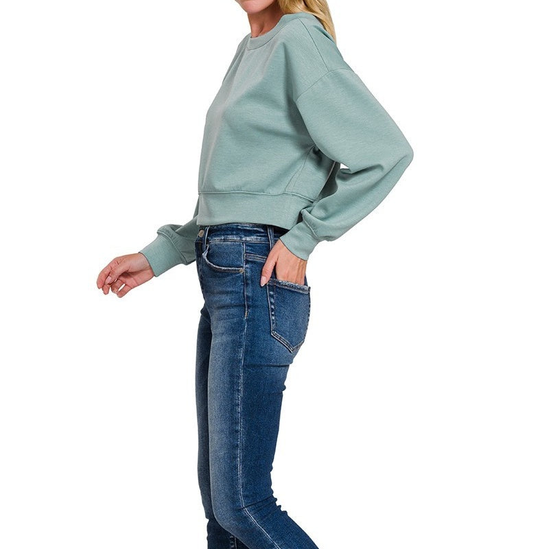 Person wearing a light green sweatshirt and blue jeans on a white background