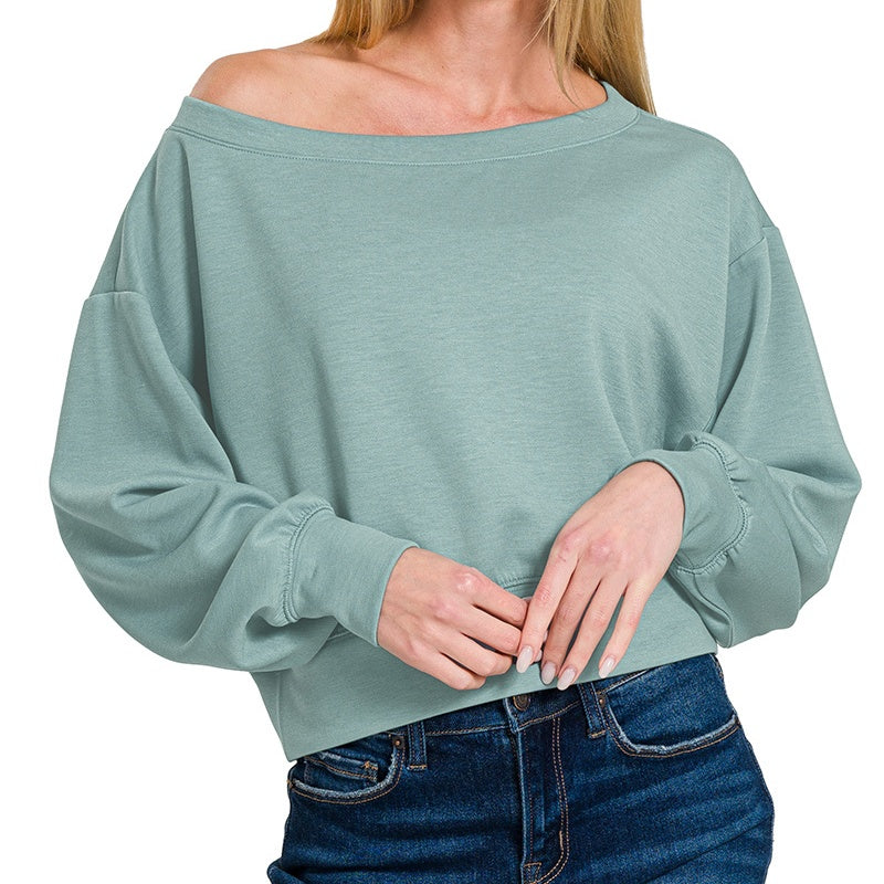Person wearing a light green oversized sweater and blue jeans on a white background