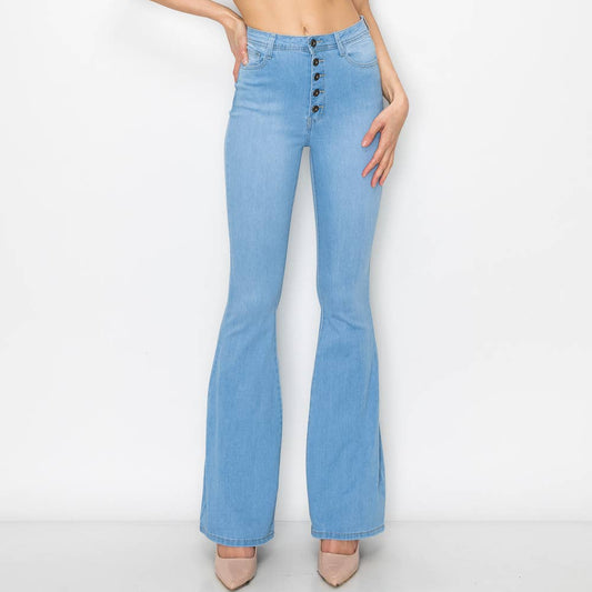 Woman wearing light blue flared jeans and a white top on a white background