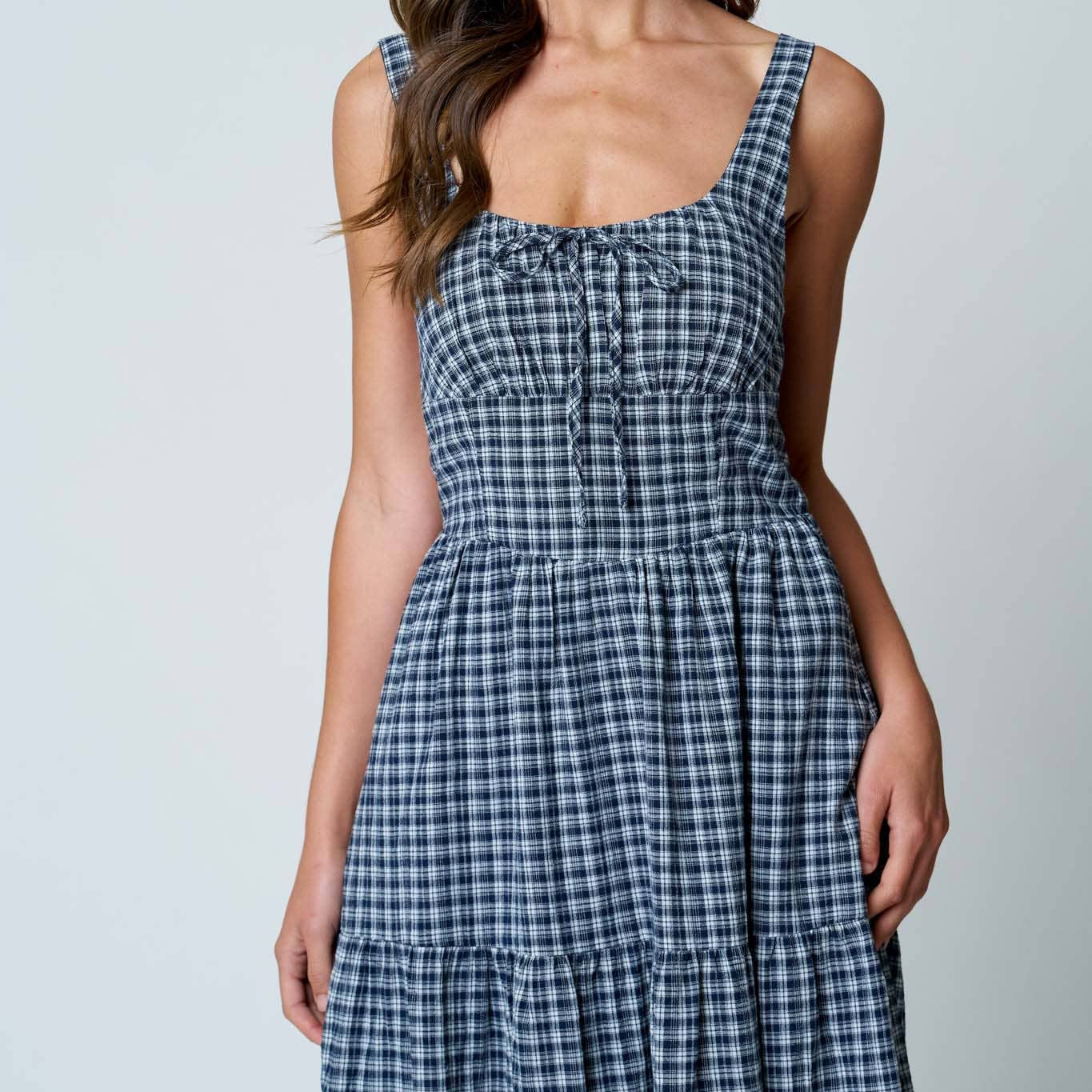 Woman wearing a blue checkered dress against a plain background