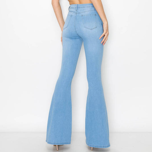 Woman wearing light blue flared jeans and a white top on a white background