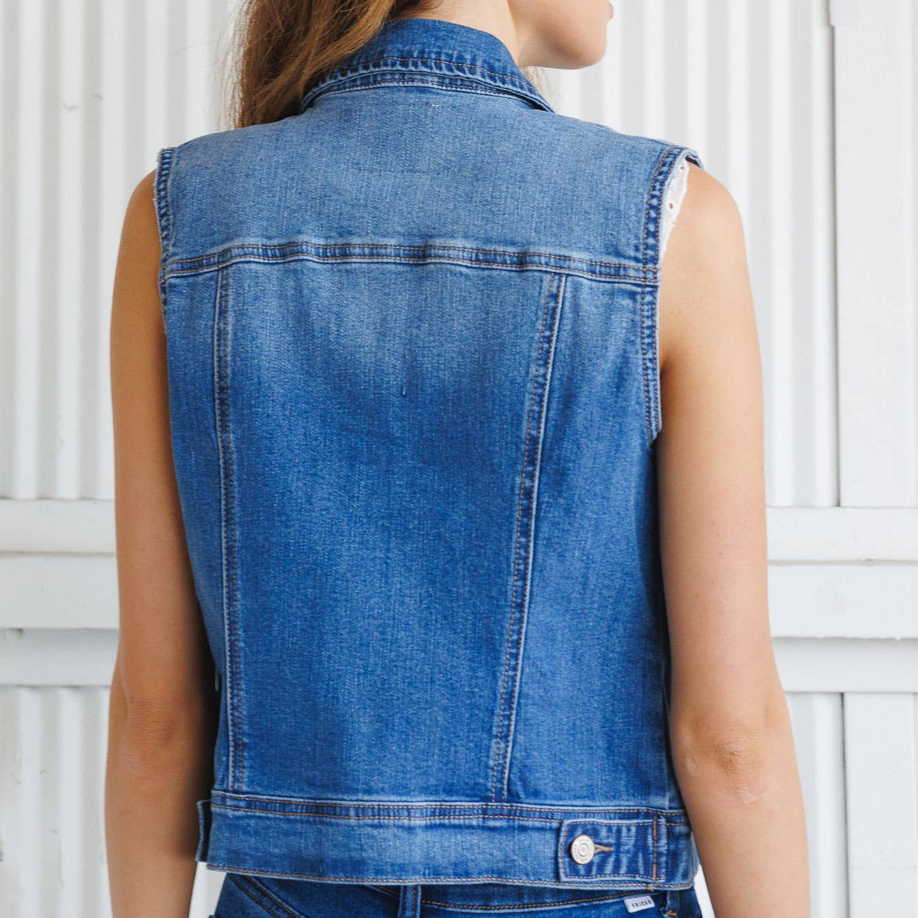 Woman wearing a blue denim vest against a white background