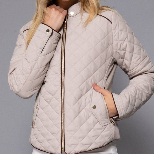 Woman wearing a beige quilted jacket against a gray background