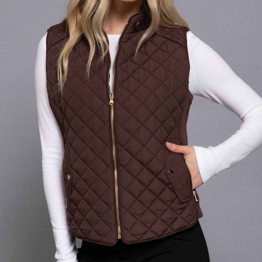 Woman wearing a brown quilted vest against a gray background