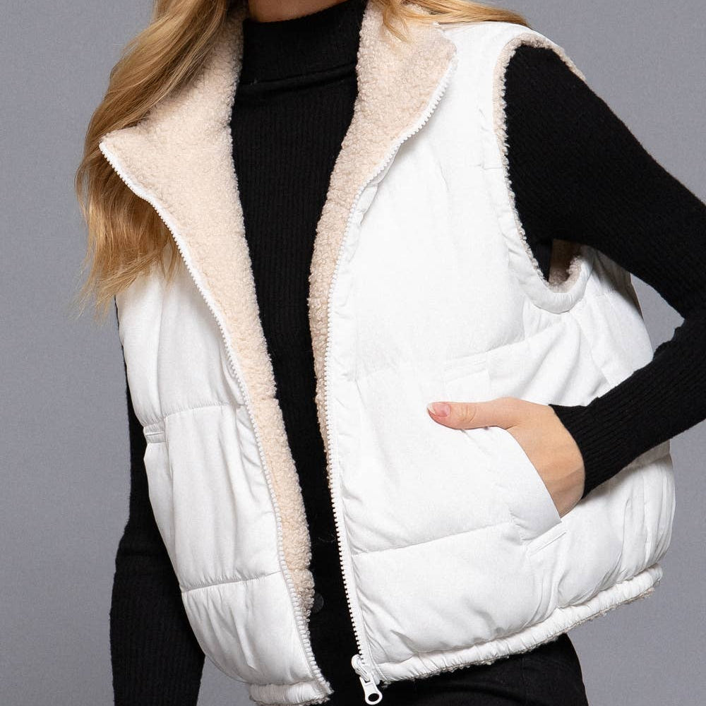 Woman wearing a white puffer vest over a black outfit on a gray background