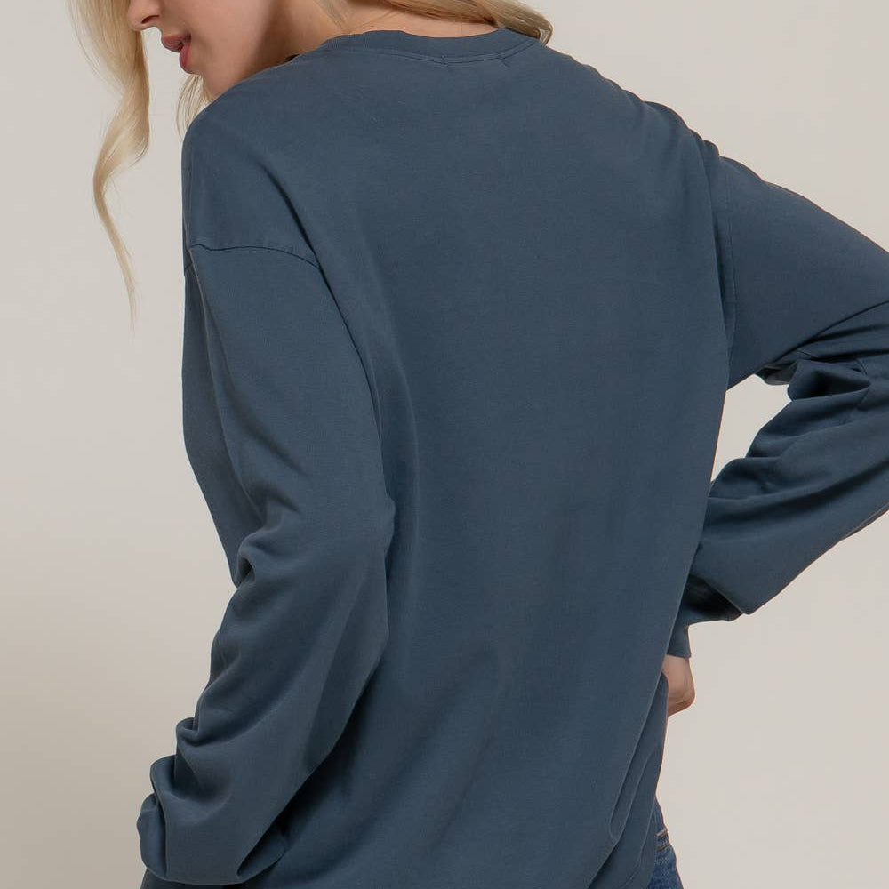 Person wearing a blue long-sleeve shirt and jeans on a plain background