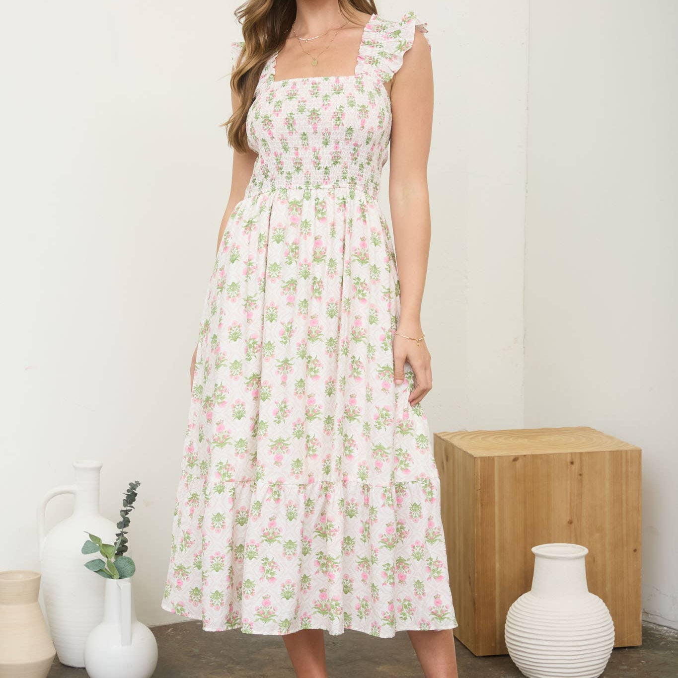 Woman wearing a floral dress standing in a room with decorative vases.
