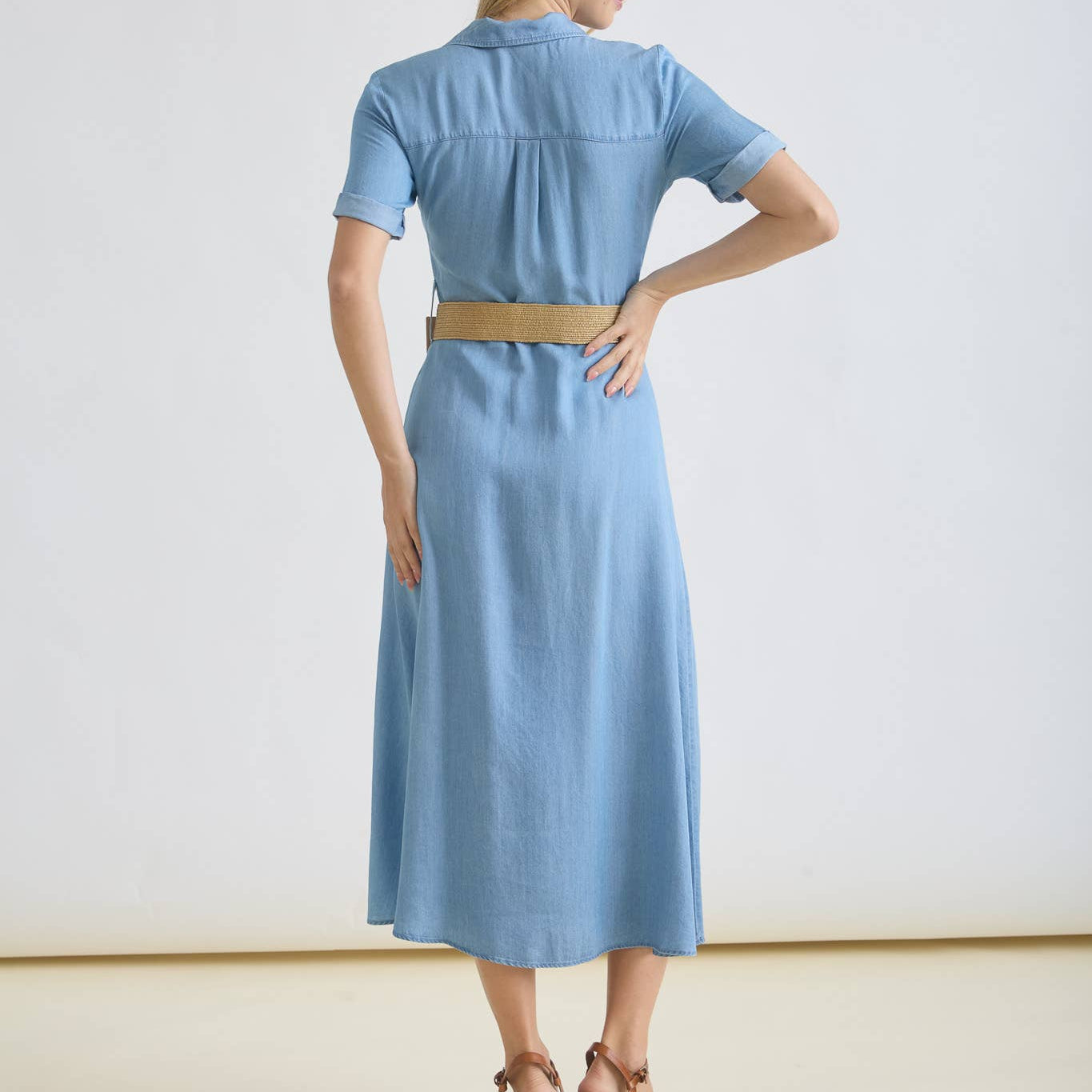 Woman wearing a light blue dress with a belt on a white background