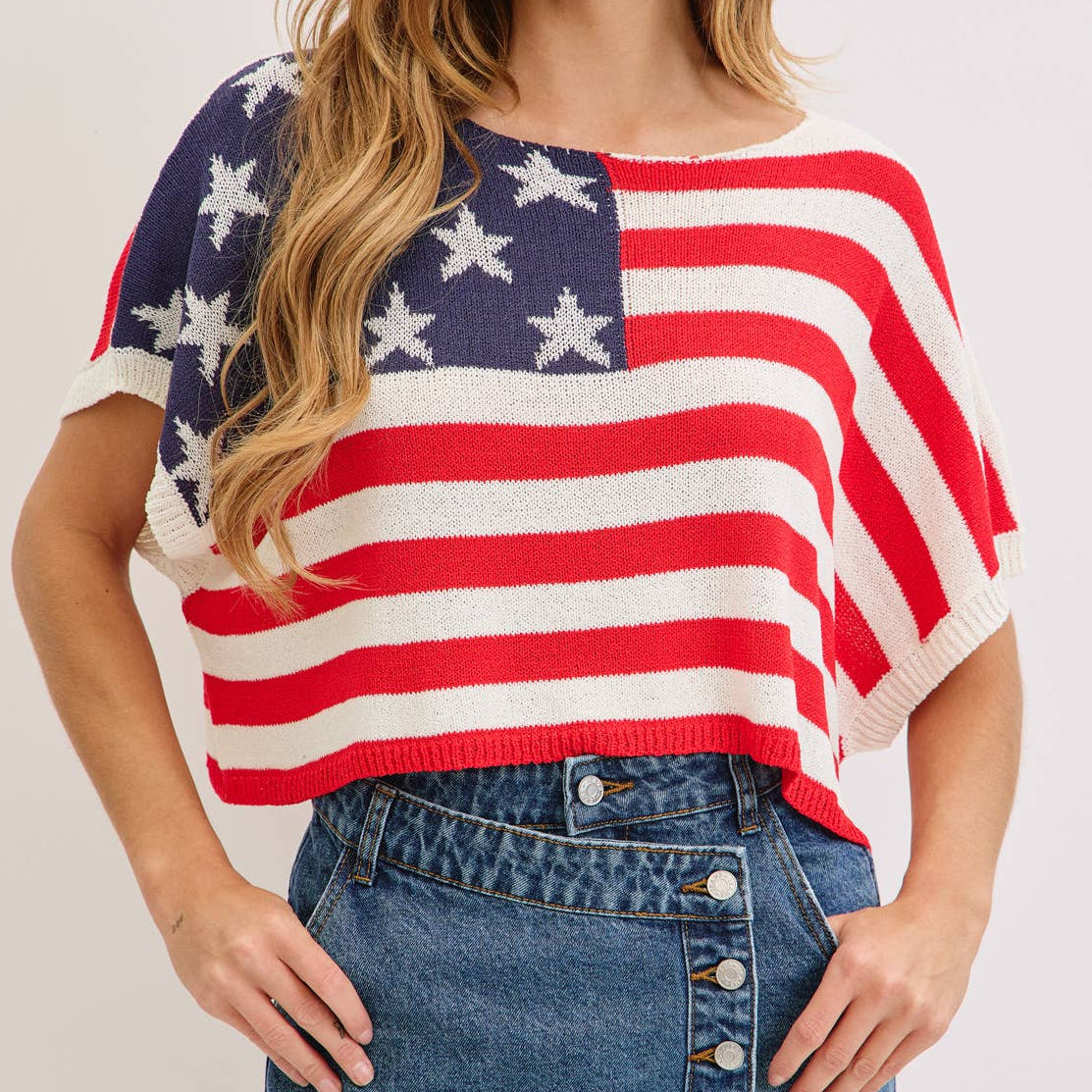 Woman wearing a USA flag shirt and denim skirt on a white background