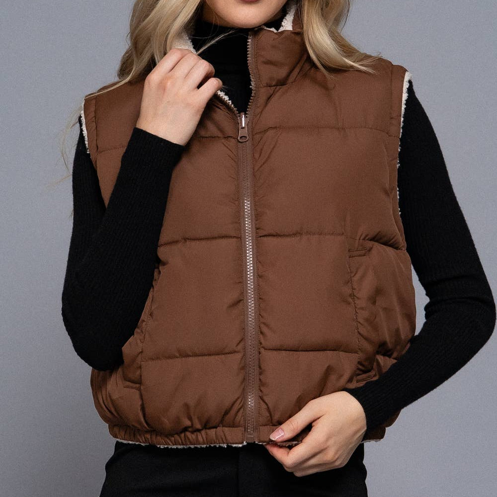 Woman wearing a brown puffer vest against a gray background