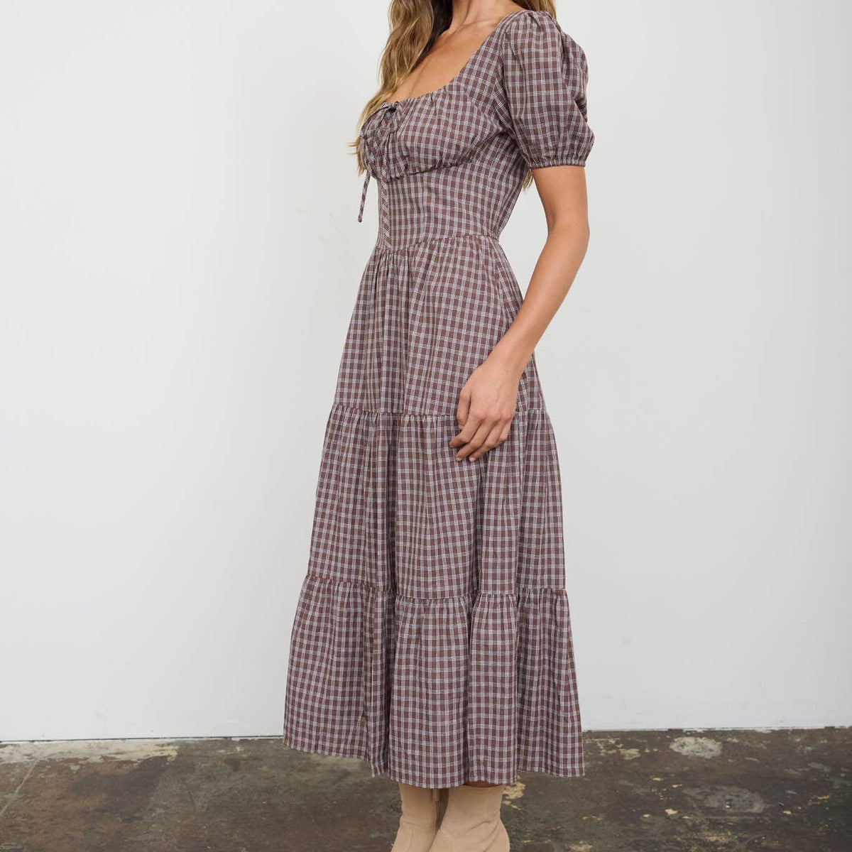 Woman wearing a checkered dress with short sleeves against a white background