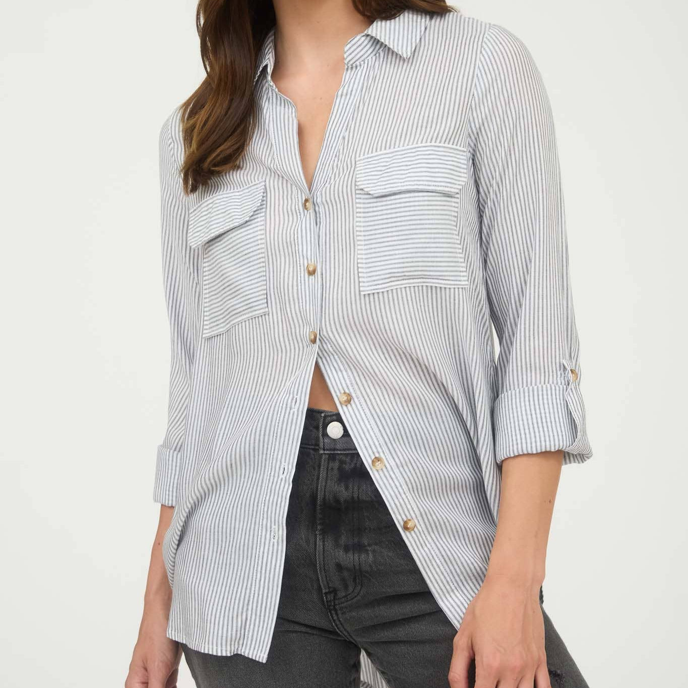 Woman wearing a light blue and white striped shirt with rolled-up sleeves on a white background